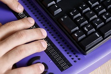 On voit des doigts qui tapent sur un clavier en braille.